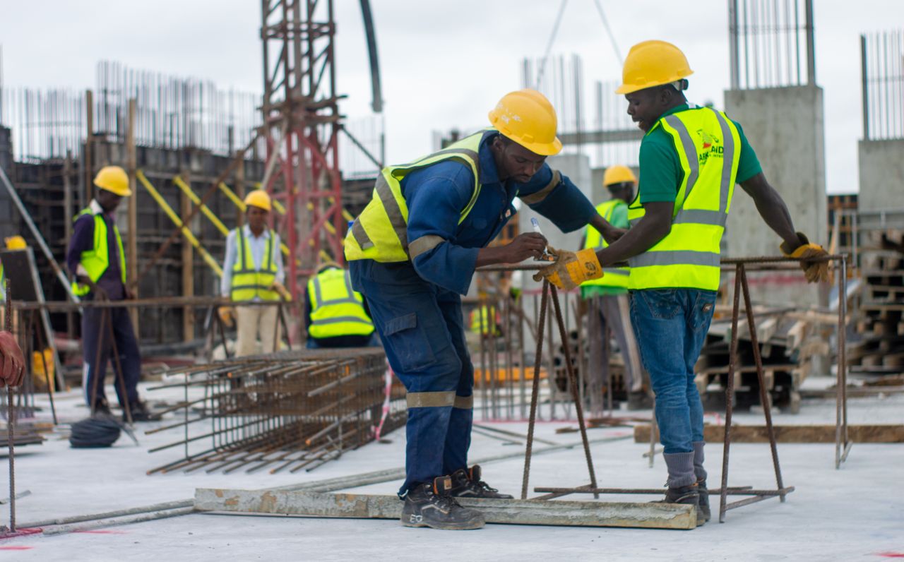 A diverse group of construction workers in safety gear at an active building site.