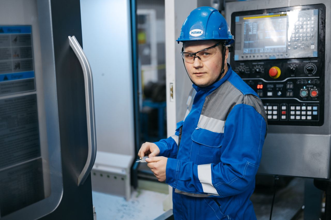 Industrial engineer in safety gear working on a CNC machine in a modern factory setting.